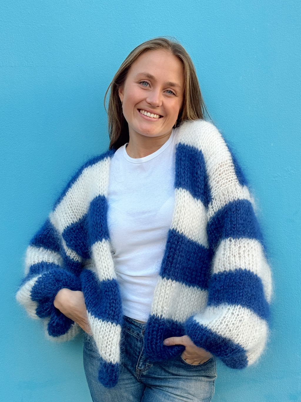 Woman wearing a blue and white striped cardigan against a blue background